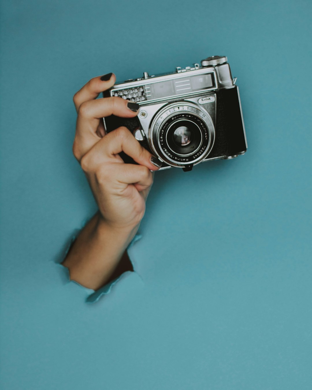 Vintage film camera and printed contact sheets on a wooden desk